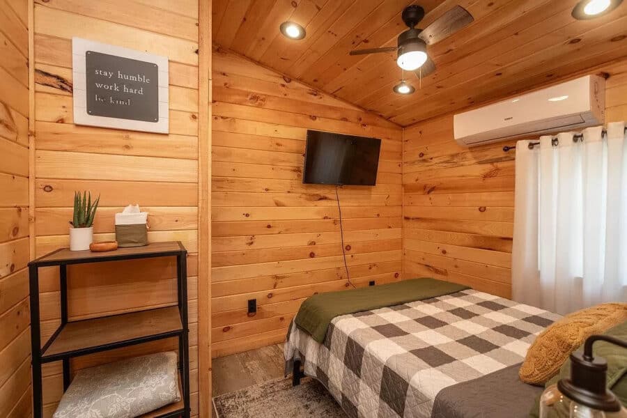 Cozy tiny house bedroom with wood paneling, bed, and modern decor.