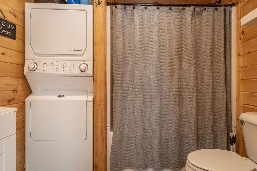 Compact laundry and bathroom area in a small woodland cabin.
