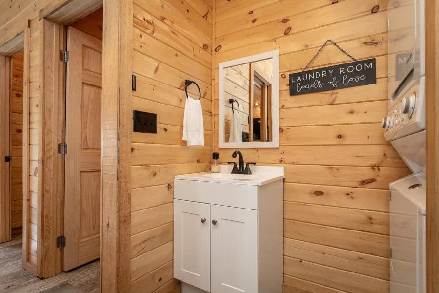 Small bathroom in a rustic tiny house cabin with wooden walls and a compact sink.