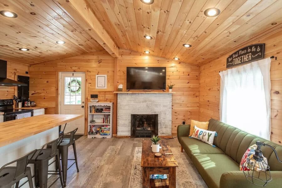 Charming tiny house living room with wood paneling, fireplace, and modern furnishings. Perfect for s.