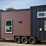 Modern tiny house on wheels with sleek black and brown exterior, compact and functional design.