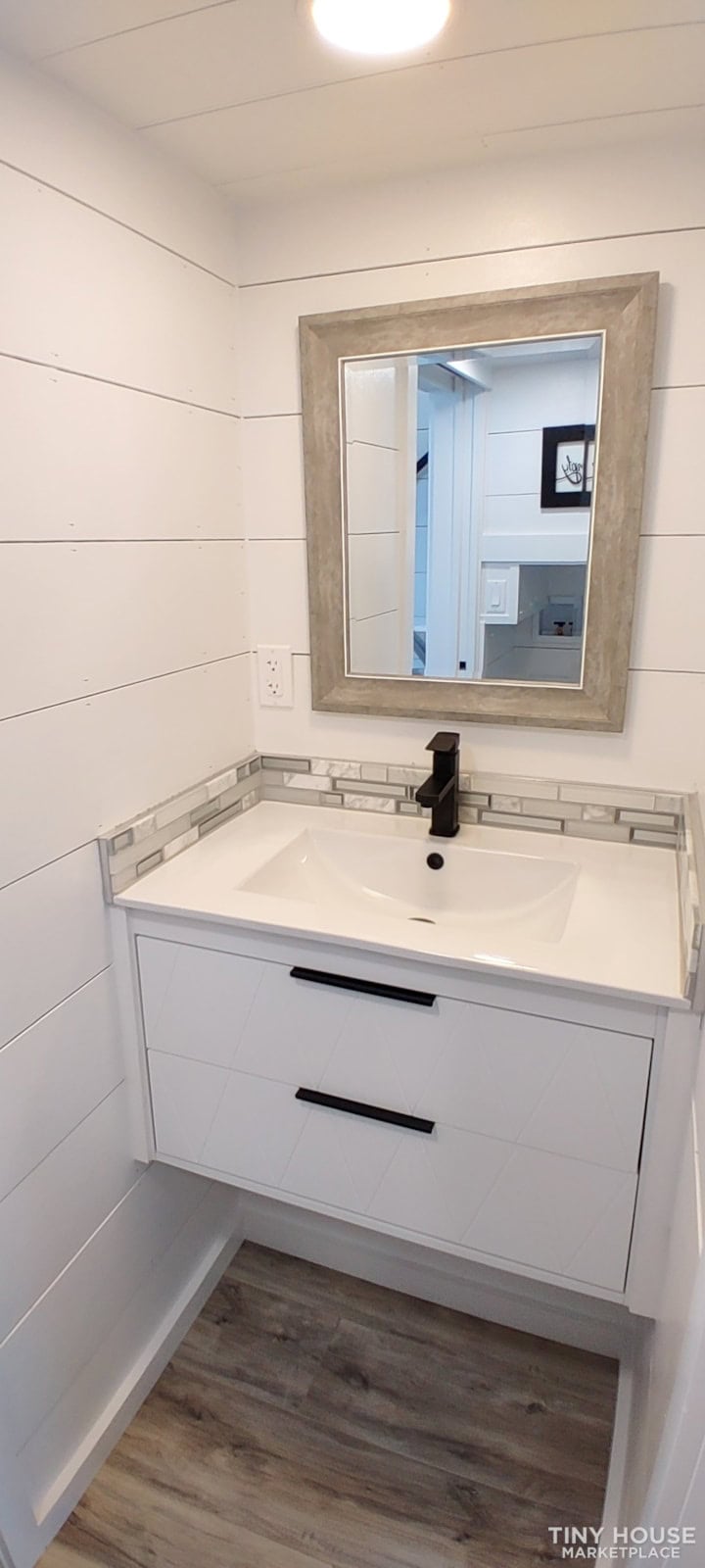 Bright tiny house bathroom with modern sink and mirror.