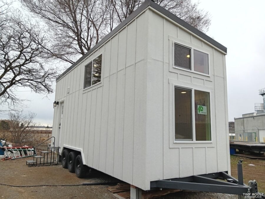 Tiny house on wheels with sleek design and large windows for natural light.
