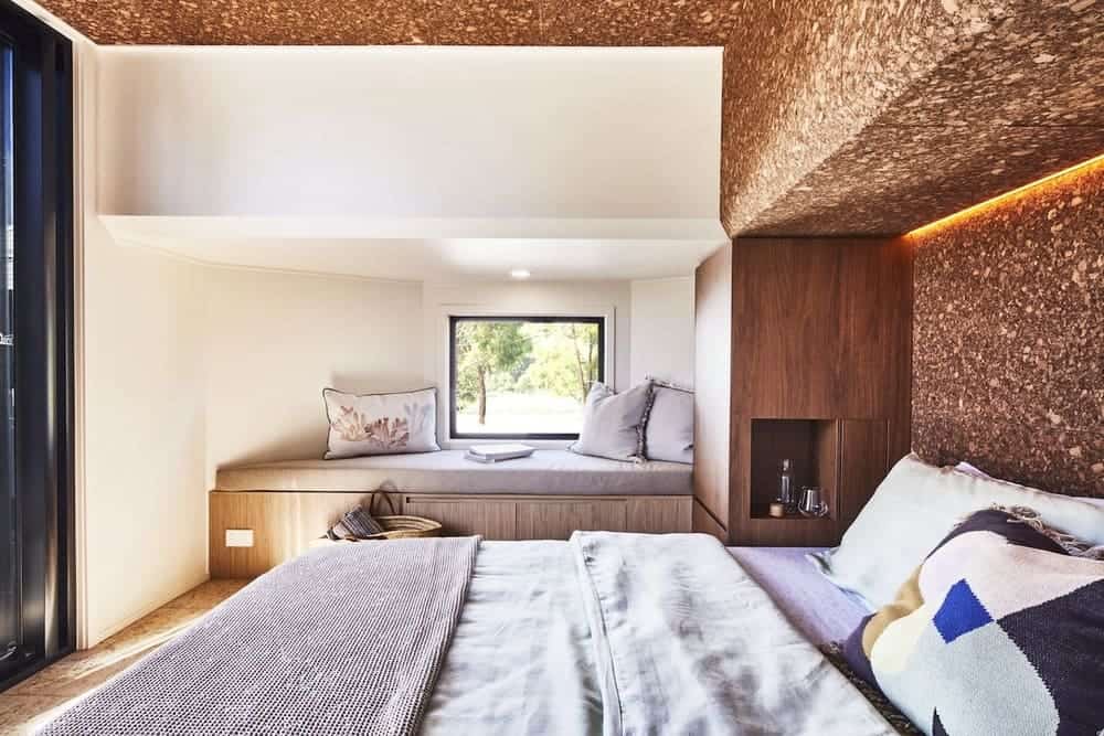 Ground-floor master bedroom in the NOOSA tiny house with white walls and a dark feature wall