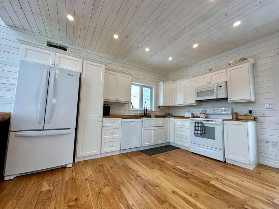 Bright tiny house kitchen with white cabinets and modern appliances.