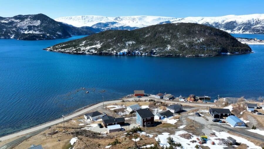 Small cabins and tiny houses nestled near a scenic lake with mountains in the background.