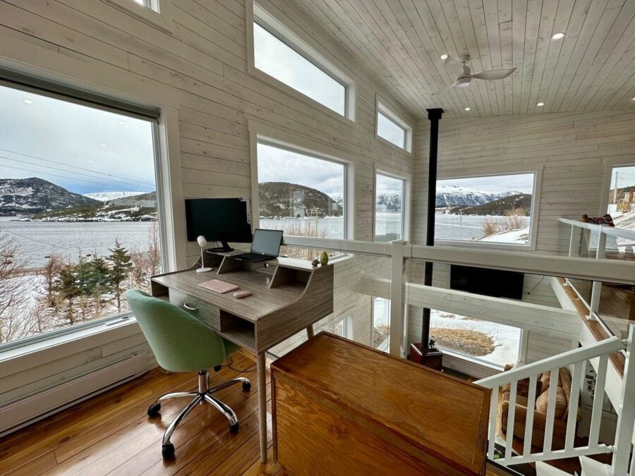 Cozy tiny house interior with large windows overlooking snowy landscape.