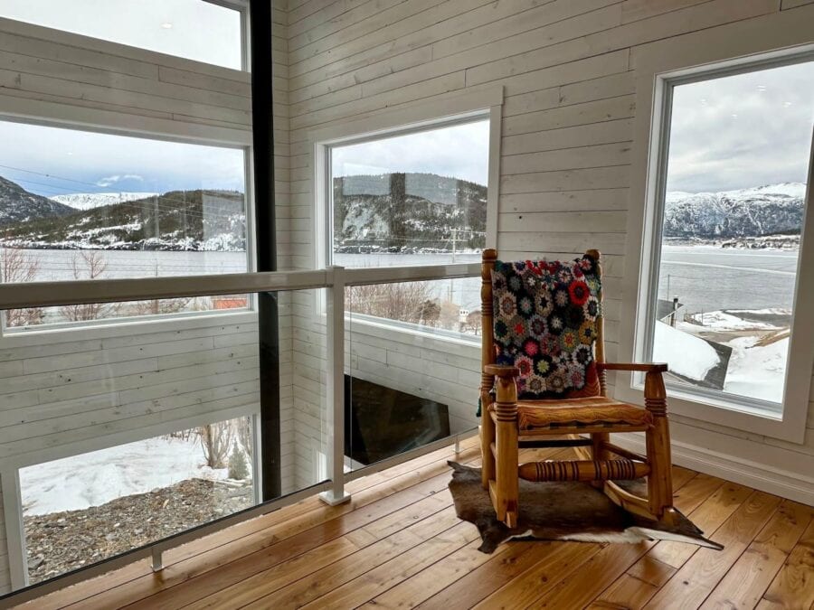 Charming cabin corner with rocking chair overlooking snowy landscape and mountains. Bright, airy spa.