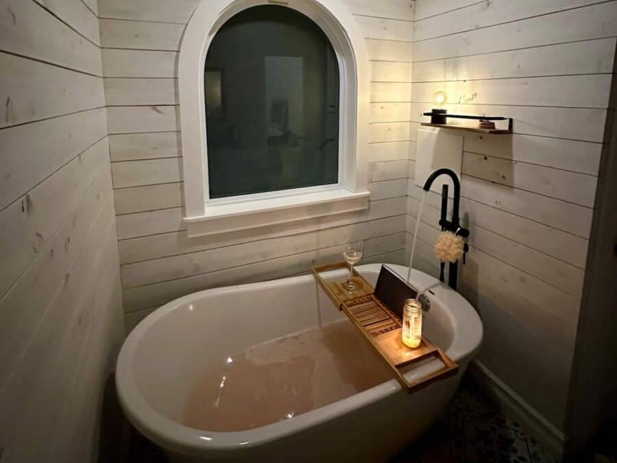 Charming bathroom with a freestanding tub, black fixtures, and soft lighting in a small cabin settin.