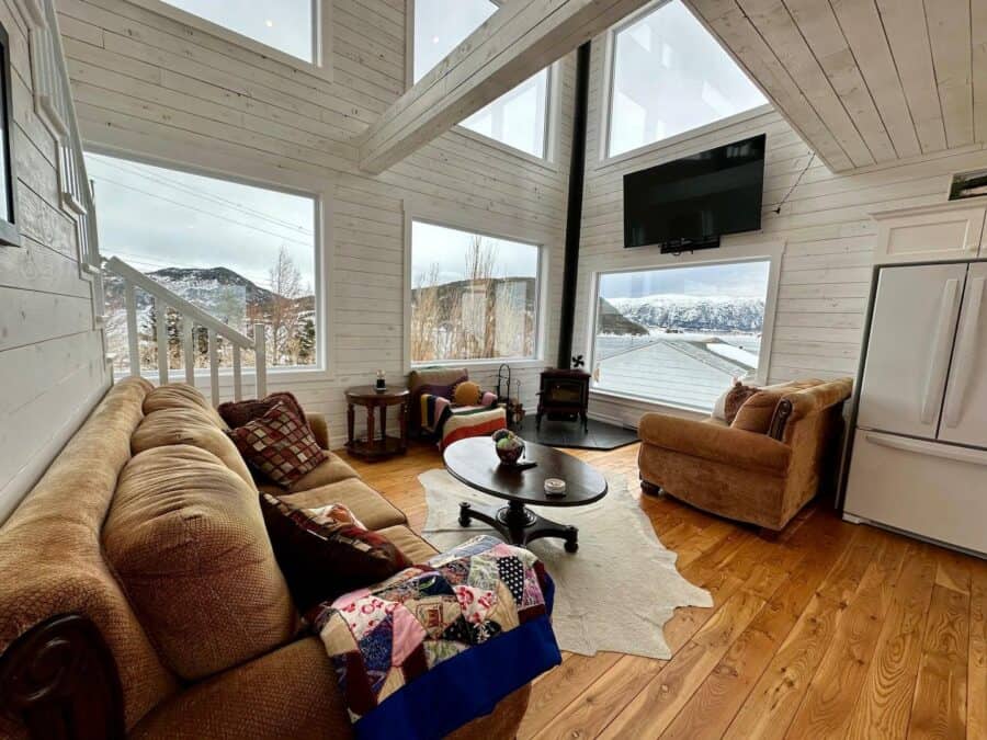 Bright living space inside a charming tiny cabin with large windows and scenic mountain views.