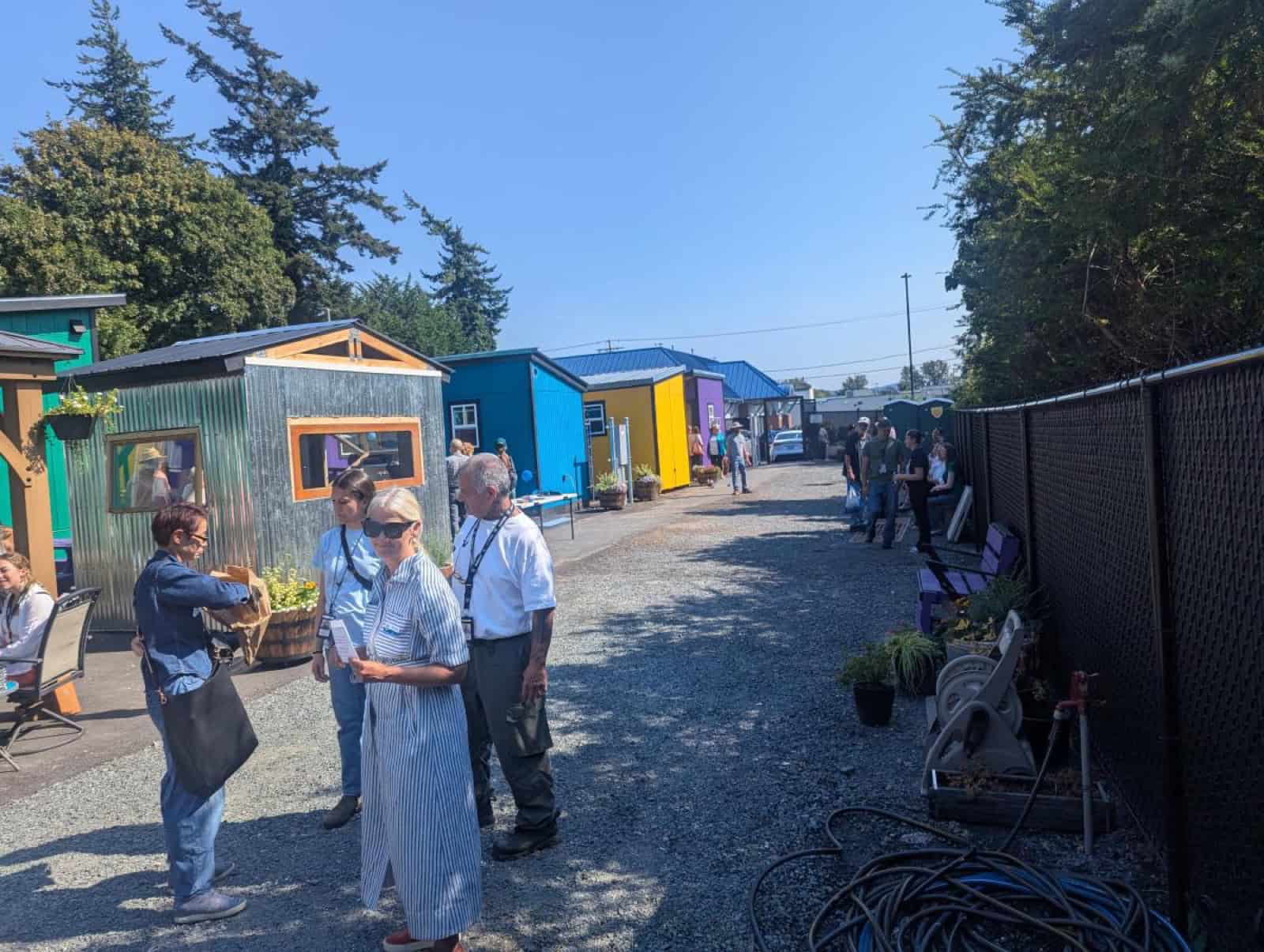 Visitors tour a lane of corrugated metal and painted tiny homes at North Haven village in Bellingham
