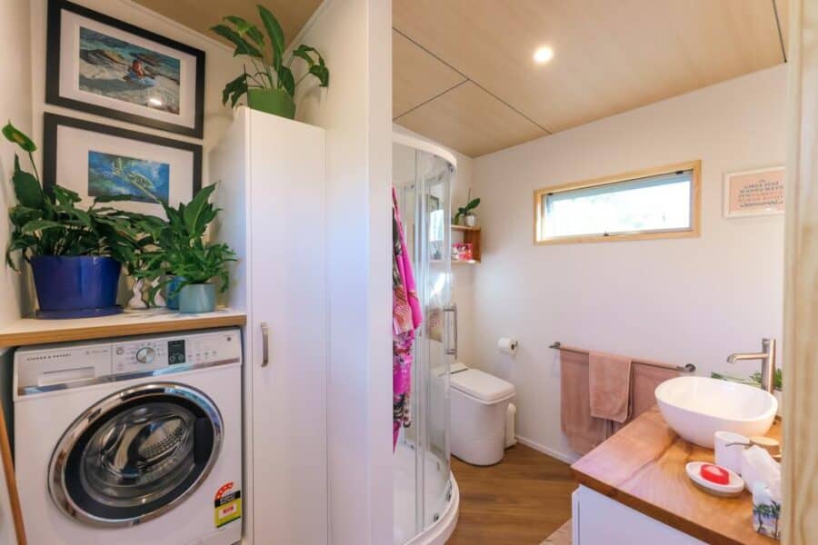 Compact tiny house bathroom with laundry and modern fixtures.