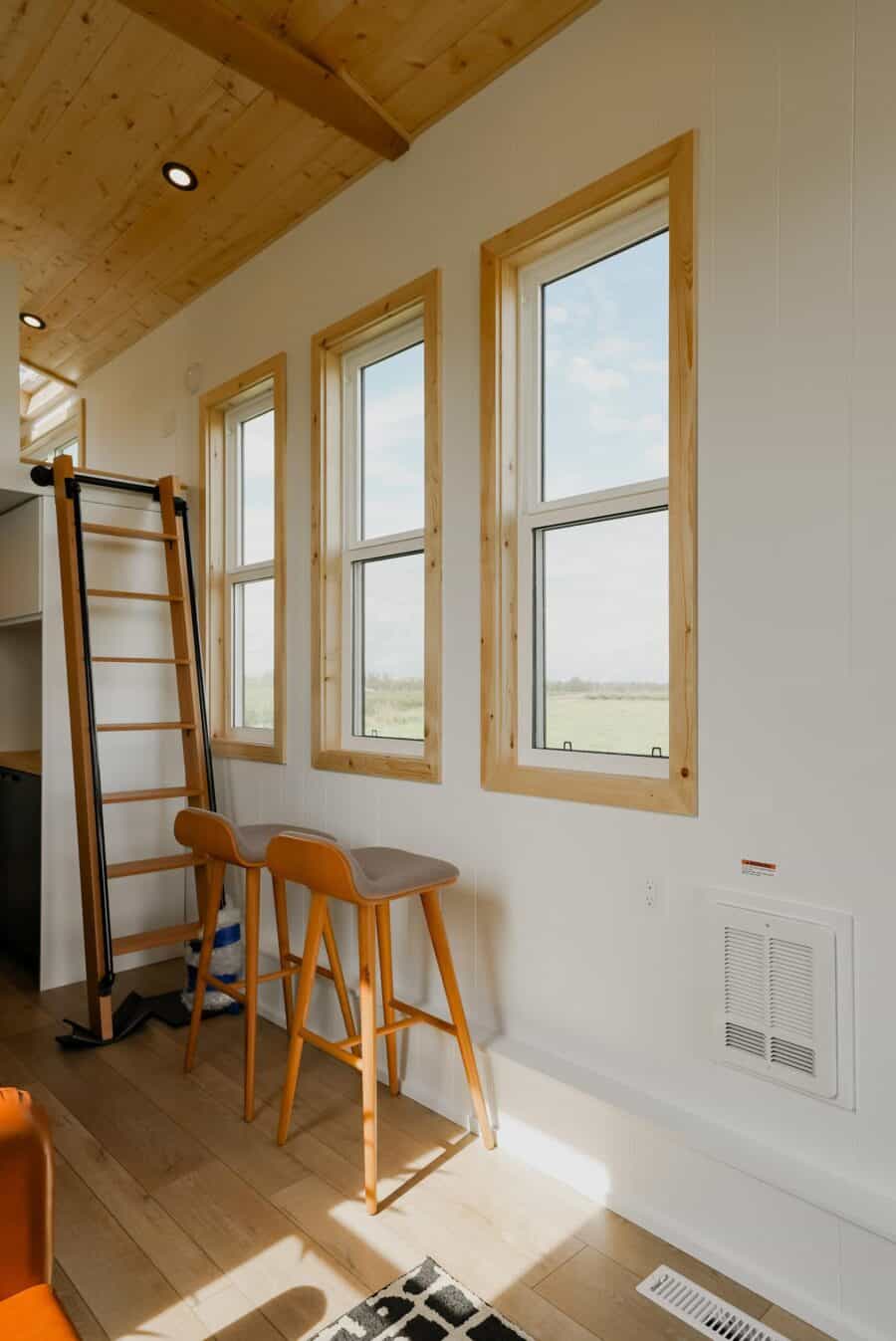 Bright tiny house with large windows and natural wood accents.