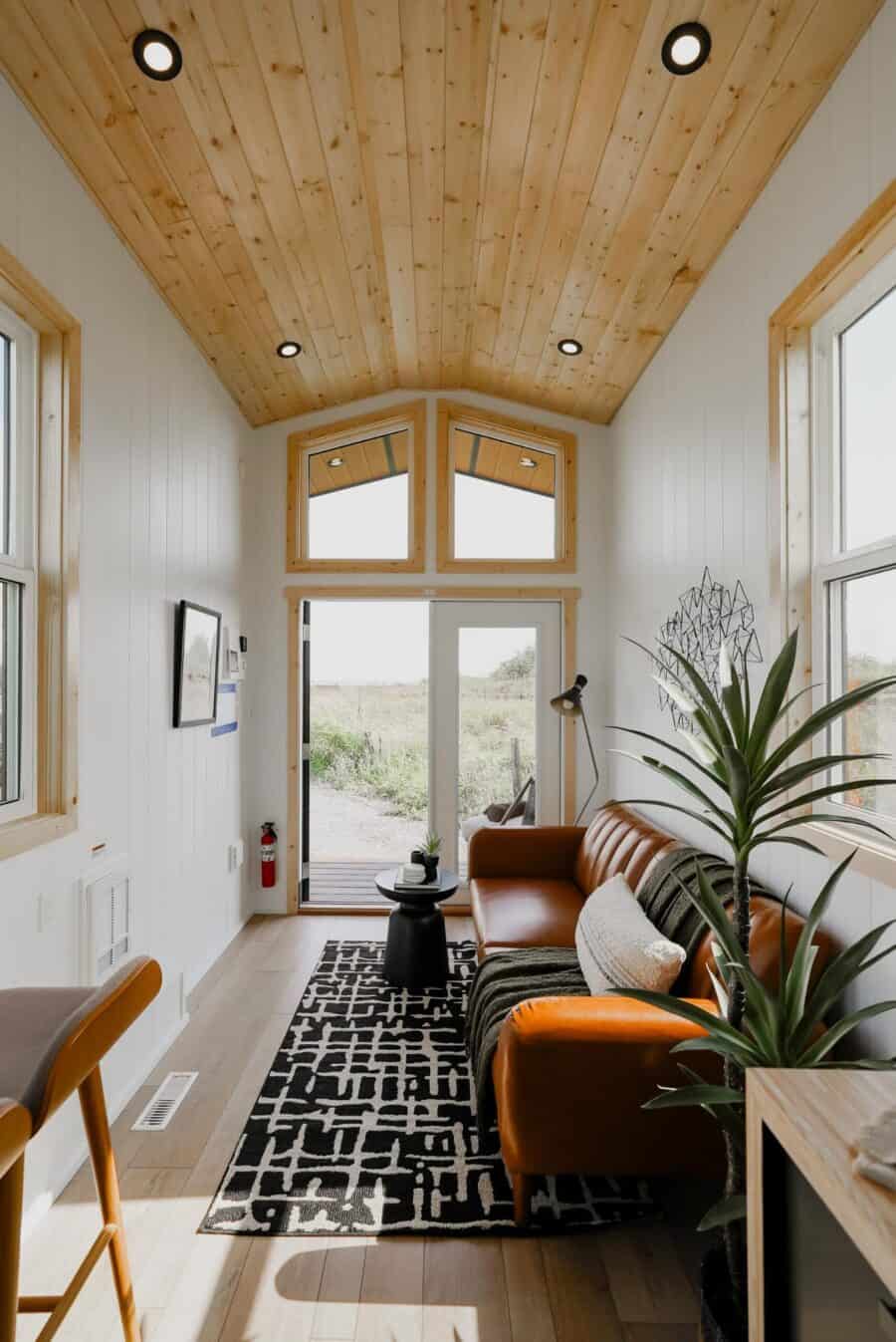 Cozy tiny house living room with natural wood accents and large windows.