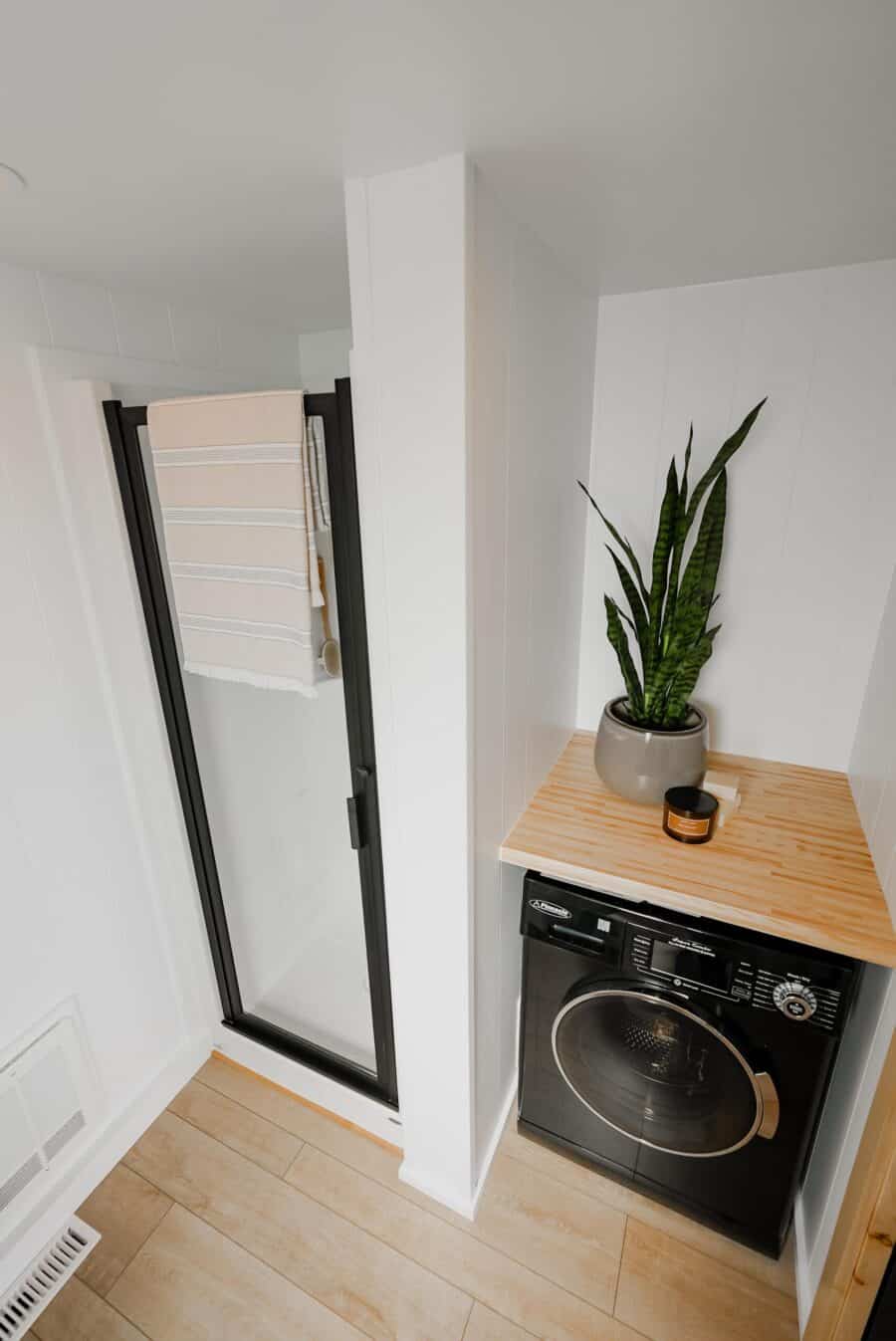 Compact laundry nook with washer and potted plant in tiny house.