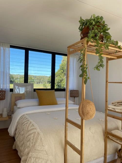 Bright tiny house bedroom with large windows and natural light.