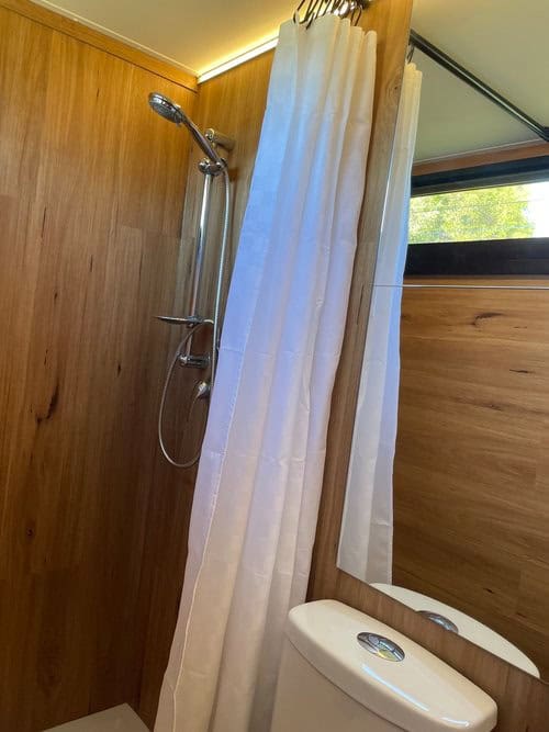 Bathroom shower with white curtain in a compact tiny house.