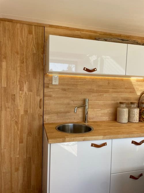 Compact tiny house kitchen with wooden accents and modern cabinetry.