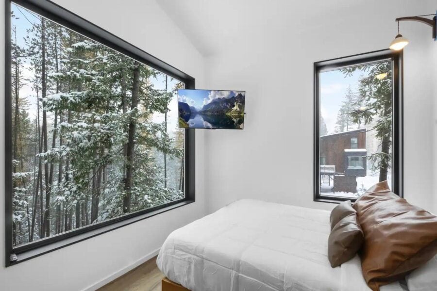 Cozy off-grid cabin on stilts surrounded by tall trees, offering a peaceful retreat on 10 acres. Mod.