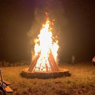 Large bonfire burning at night during an off-grid workshop camp