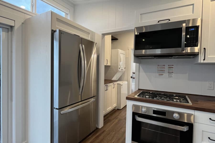 Compact kitchen in a tiny house with stainless steel appliances and modern cabinetry.