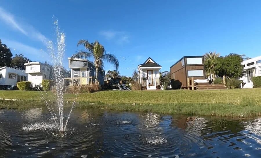 Tiny house community with modern small homes near a pond and fountain.