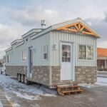 Compact tiny house with modern design and stone accents for small space living.