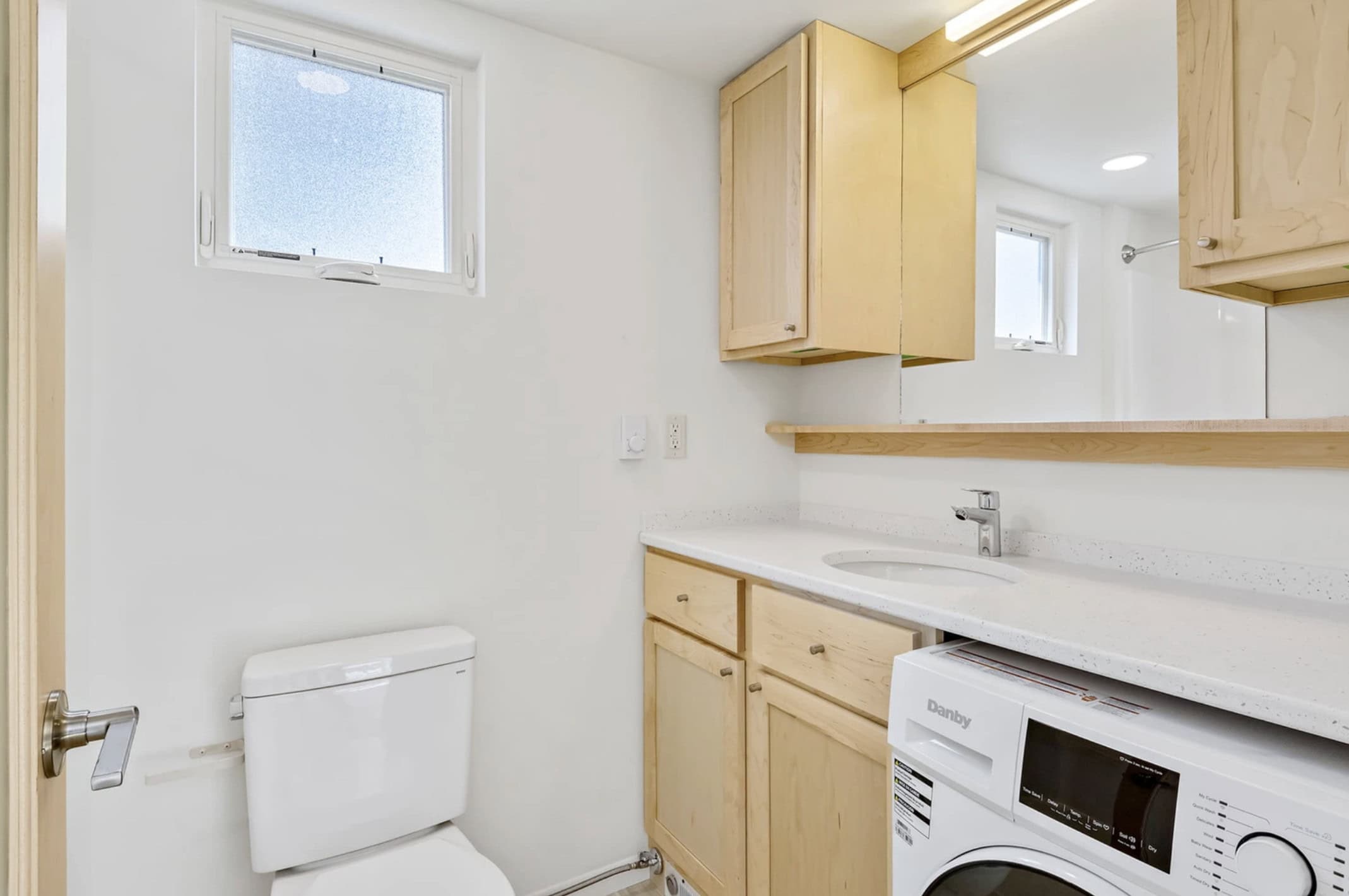 Full bathroom with stone-top vanity and in-home washer dryer in the Escape N2