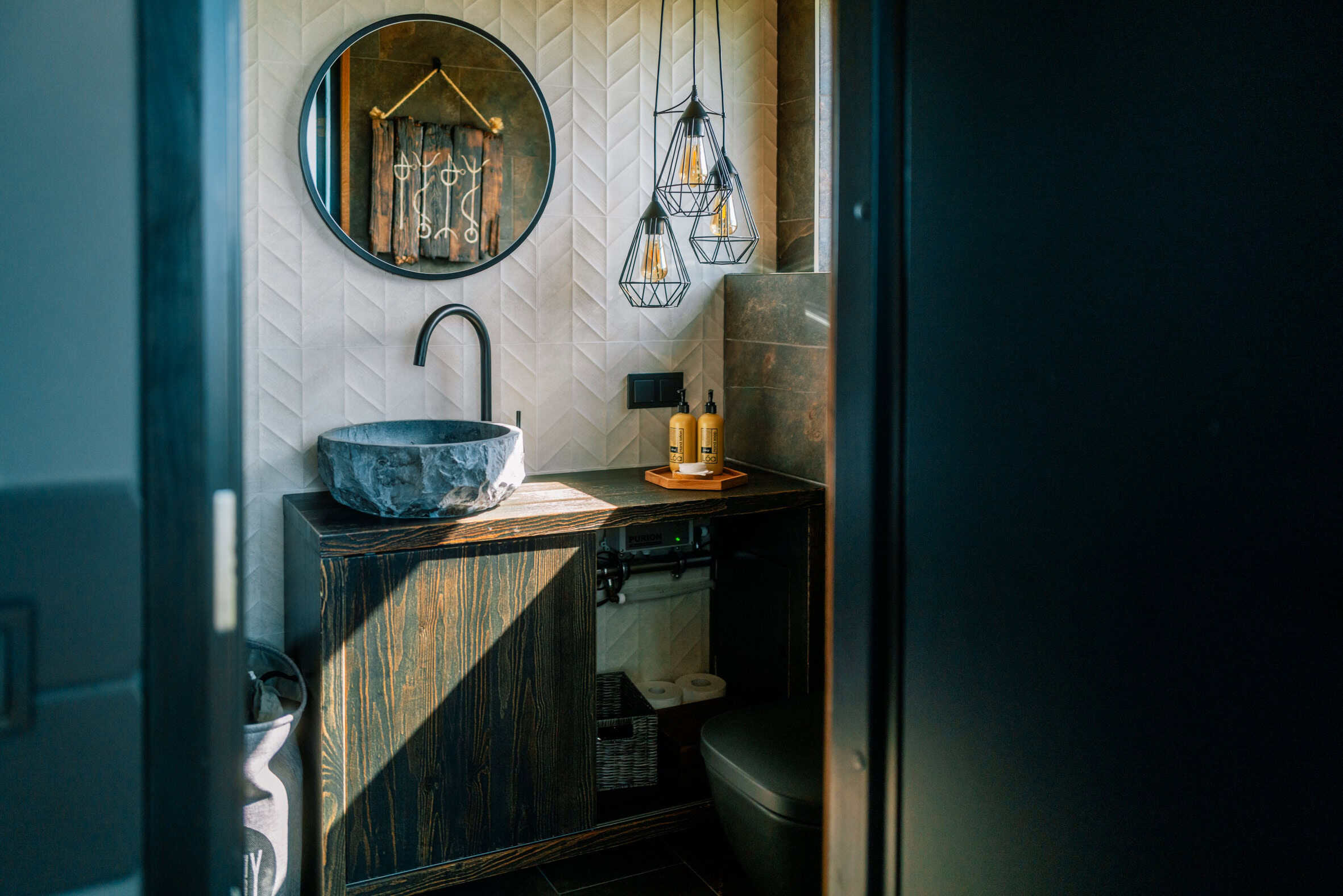 Bathroom inside a Panorama Glass Lodge with stone vessel sink and round mirror