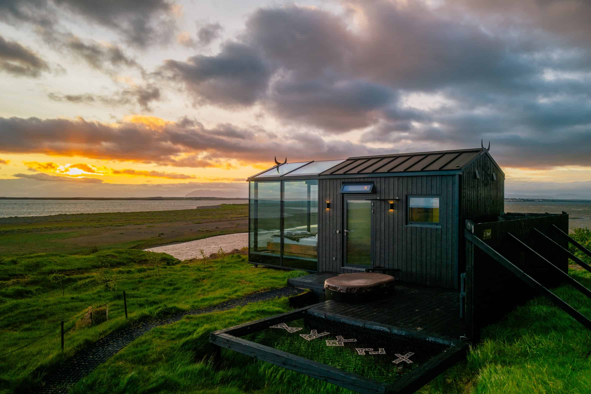Exterior of a black-clad Panorama Glass Lodge with glass front at sunset