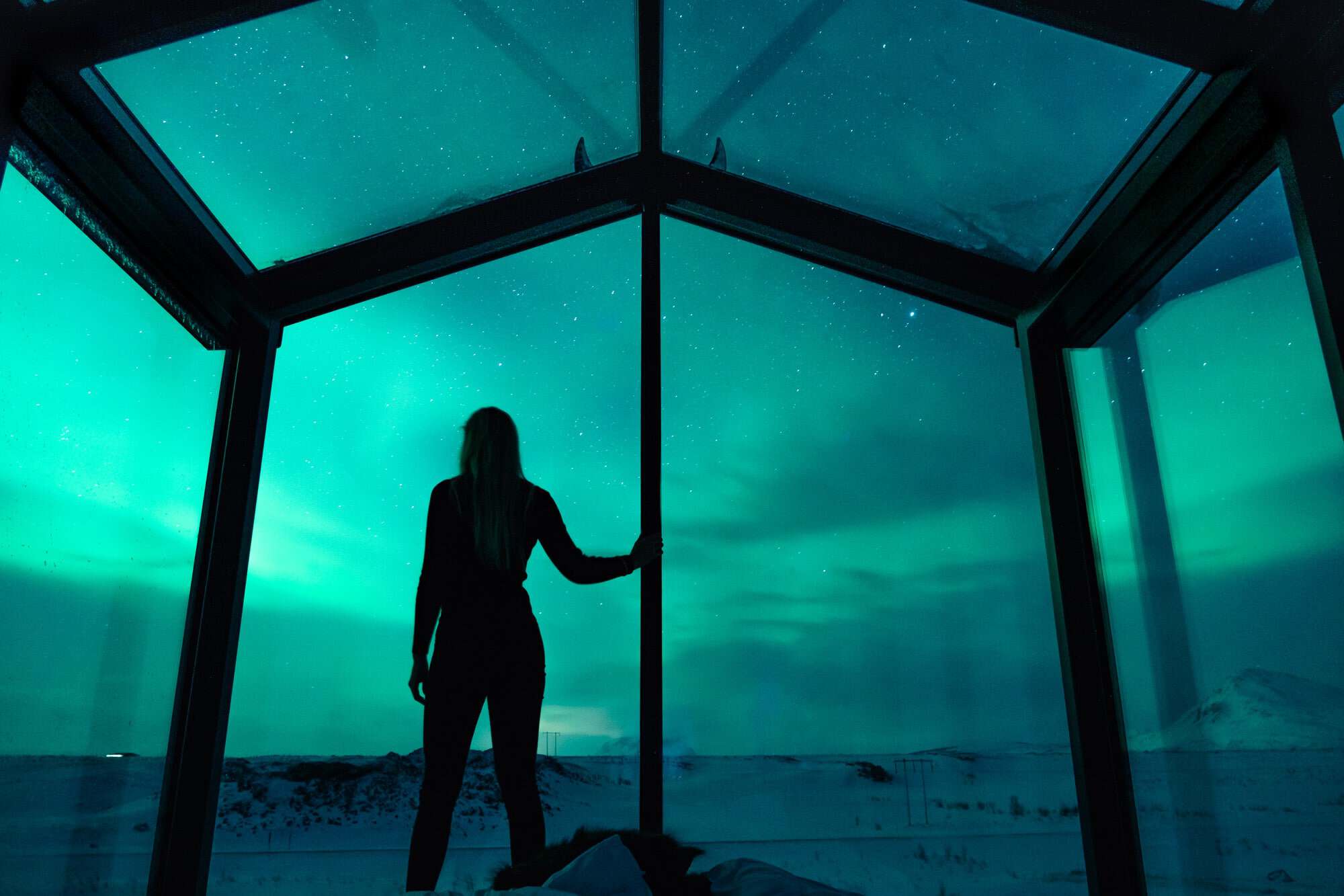 Aurora glowing through the glass roof and walls of a Panorama Glass Lodge