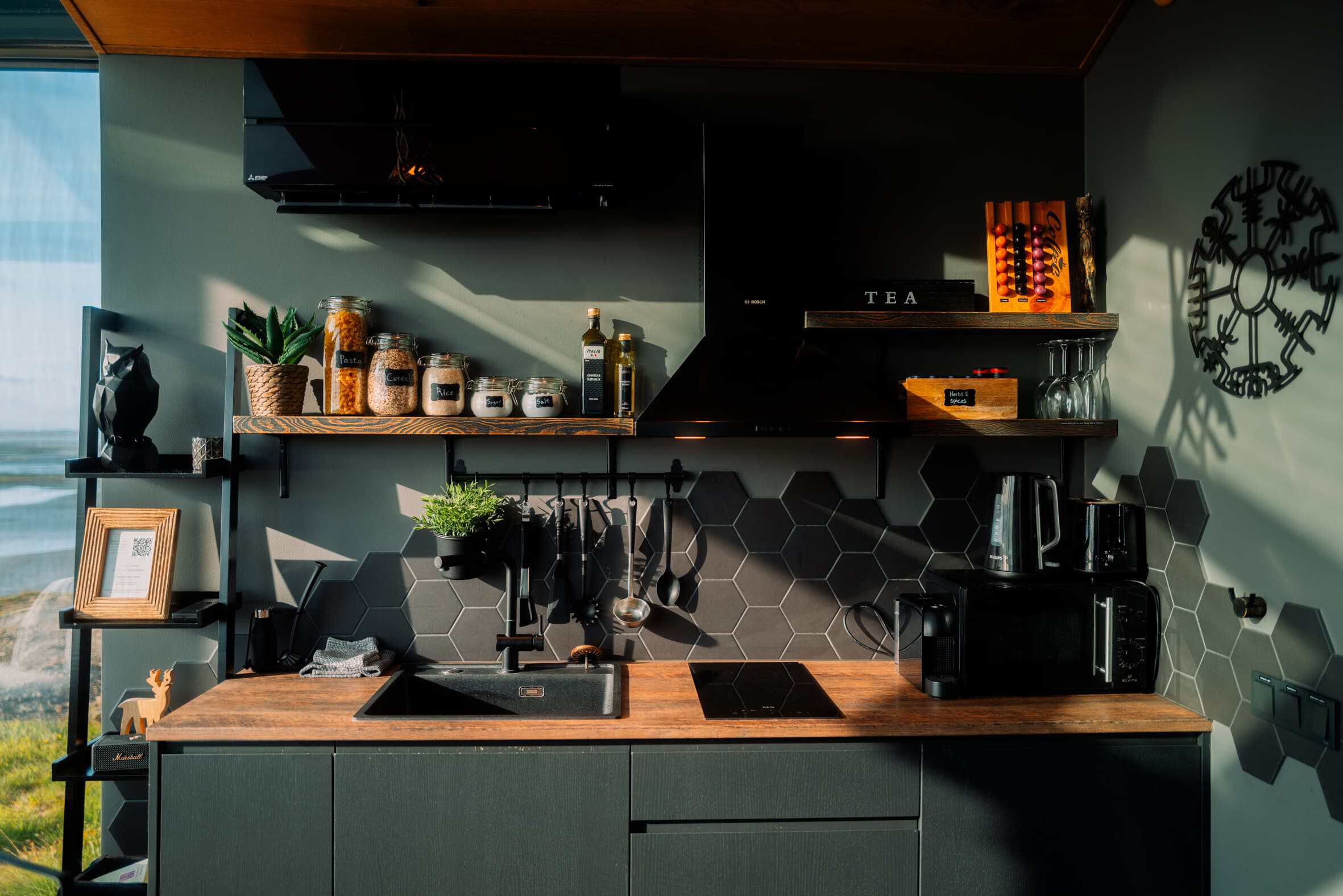 Compact fully equipped kitchen inside a Panorama Glass Lodge with hexagon tile backsplash