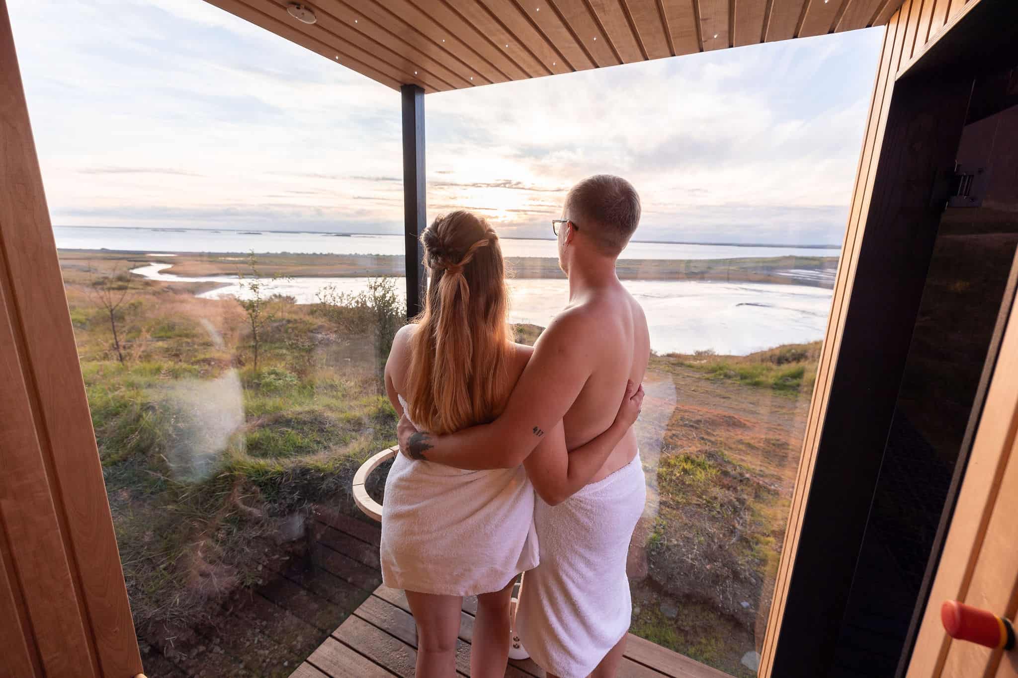 Couple looking out over the Icelandic countryside from a sauna at Panorama Glass Lodge