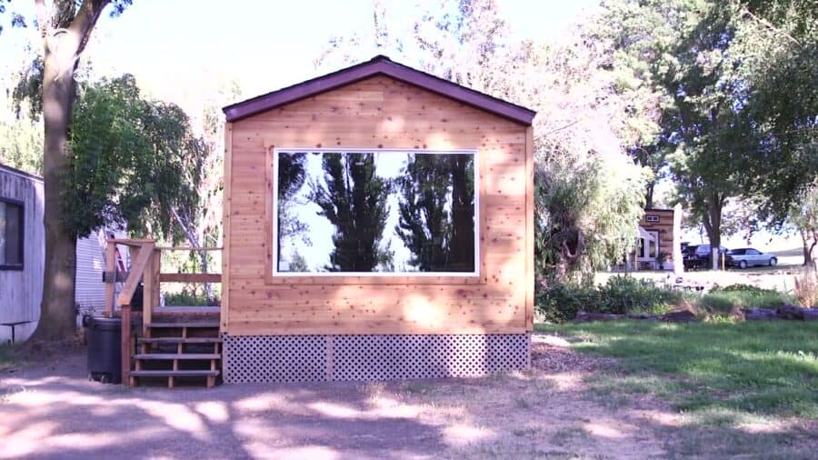 Cedar-clad tiny cabin with a large picture window and entry stairs at Park Delta Bay