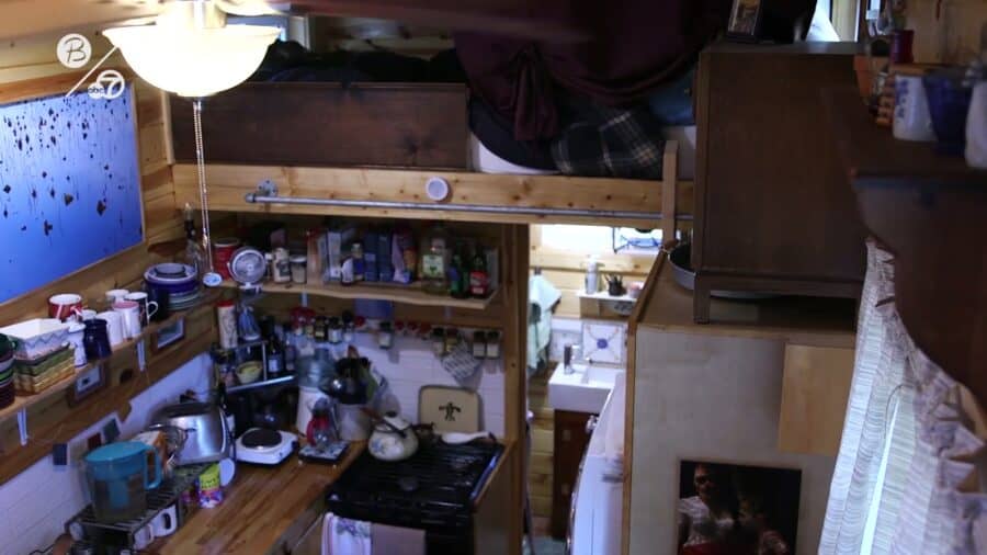 Compact tiny house kitchen with open shelving and a gas range inside Corrine Corley's home at Park Delta Bay