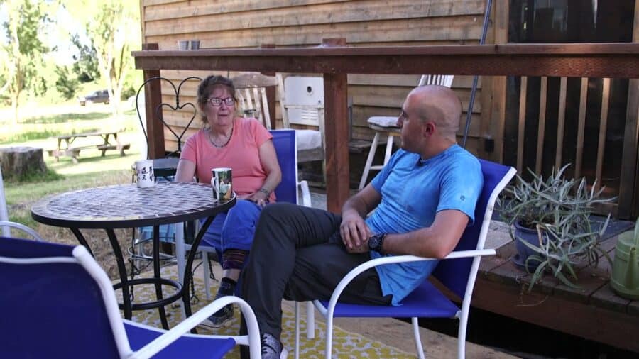 Neighbors chatting over coffee at a patio table outside a tiny house at Park Delta Bay