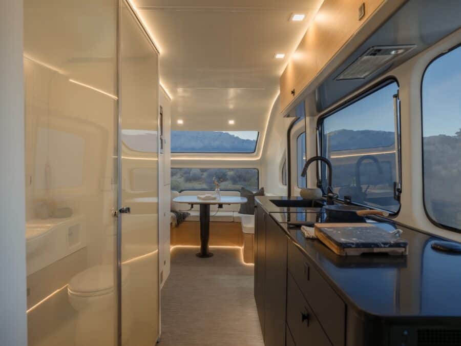 Interior of a tiny house with a sleek kitchen, large windows, and scenic mountain views.