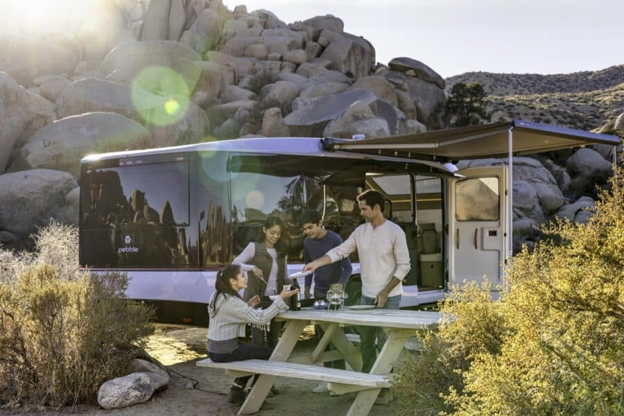 Family enjoying outdoor meal at Pebble Flow electric trailer in nature.