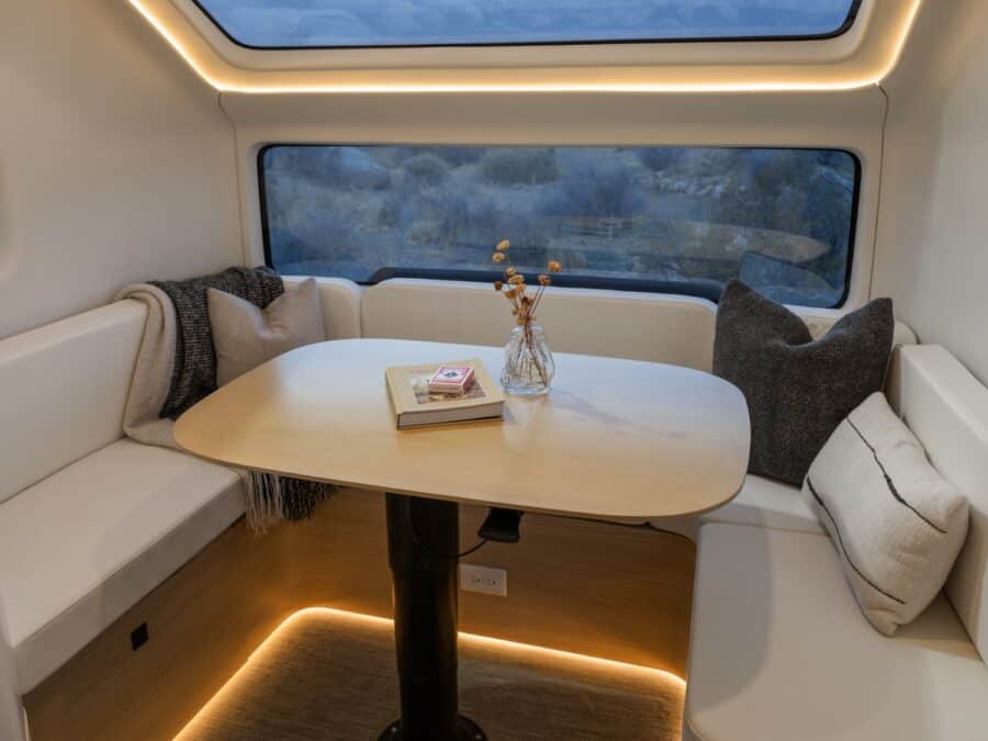 Compact tiny house dining nook with built-in seating and large window view.