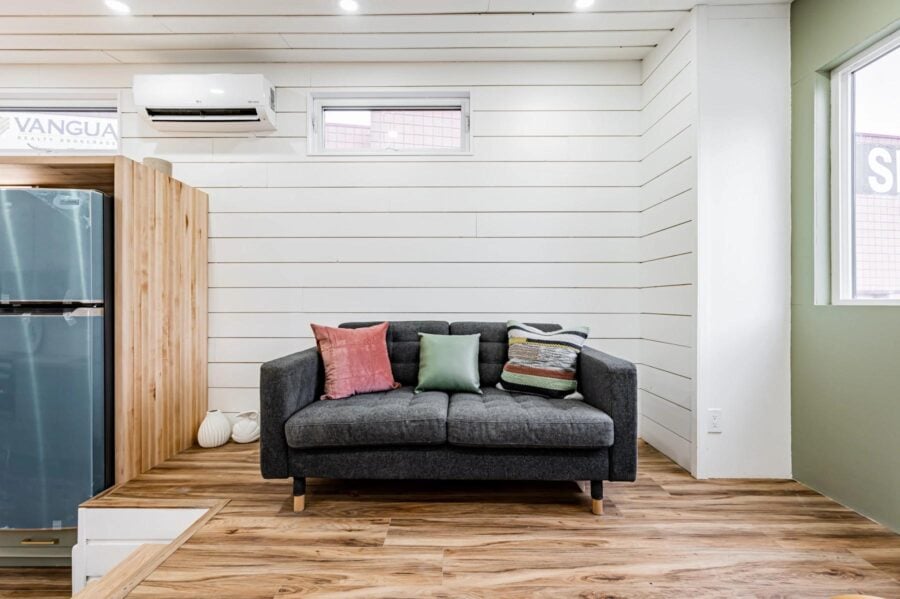 Cozy sofa inside a compact pine needle tiny home with modern decor and natural light.