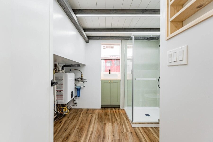 Small bathroom with shower and utility space in a tiny home, showcasing efficient use of space.