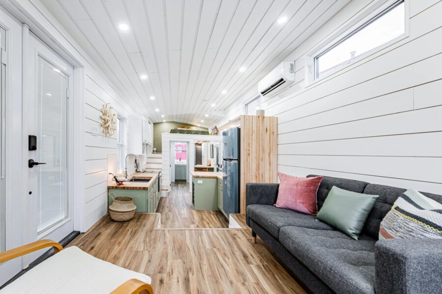 Cozy tiny home interior with white shiplap walls, wooden accents, and comfortable seating.