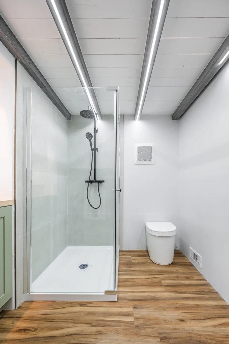 Bathroom interior of a tiny house with a glass shower enclosure and modern fixtures.