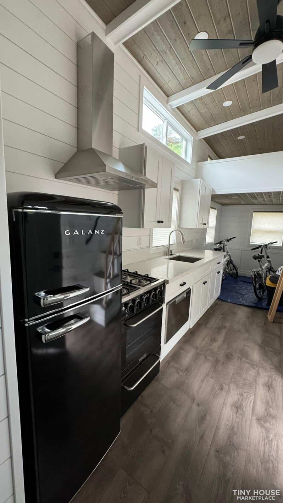 Compact kitchen with modern appliances in a sage green tiny house.