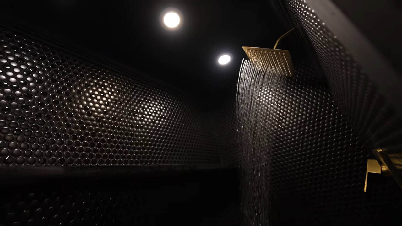 Penny-tile shower with a gold rainfall showerhead inside the van