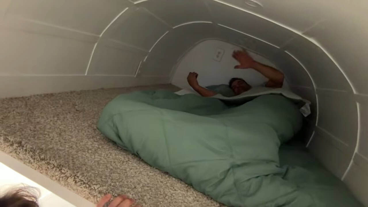 Upstairs sleeping loft with a curved ceiling and green bedding