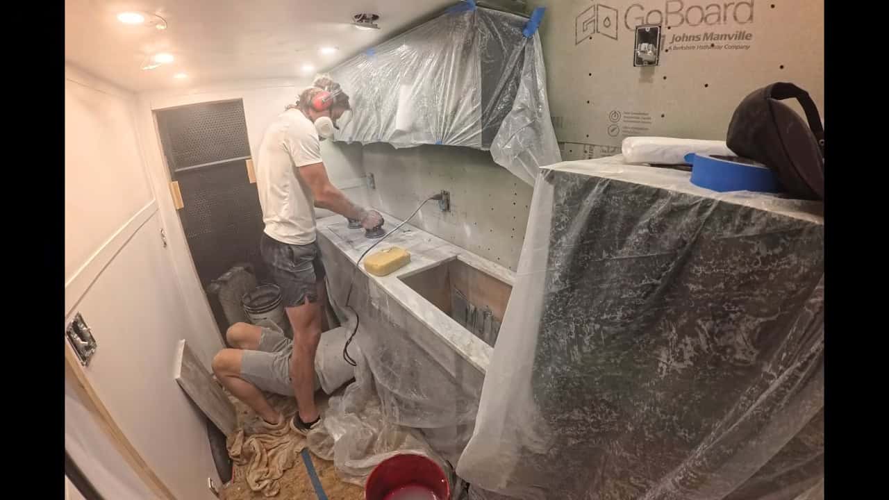 Builder sanding the bathroom wet-area walls and counter during construction