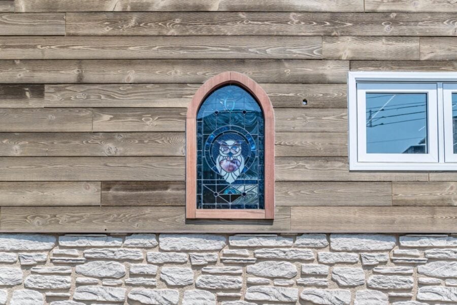 Stained glass window featuring a purple heart design on a tiny house exterior.