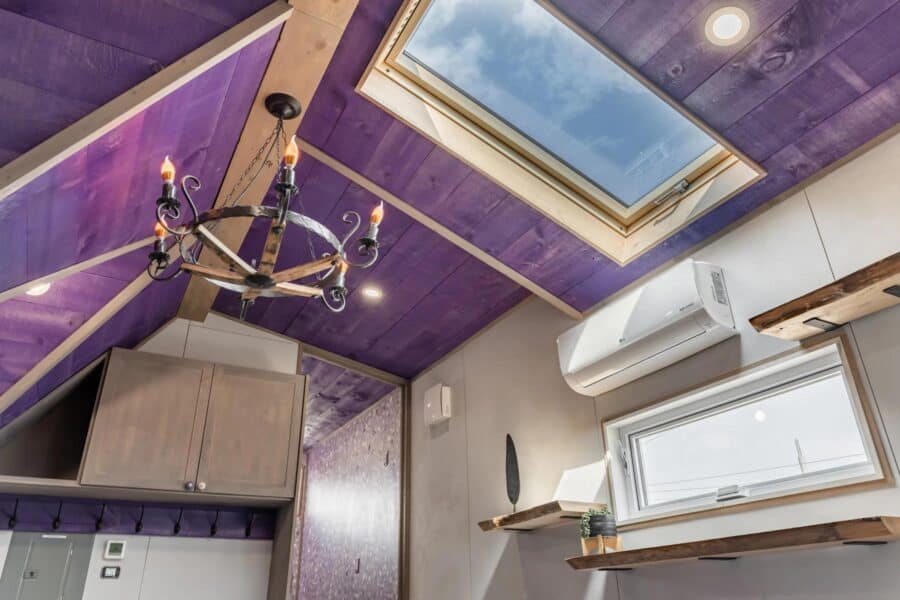 Cozy tiny house interior featuring a skylight, purple accents, and contemporary decor by Acorn Tiny.
