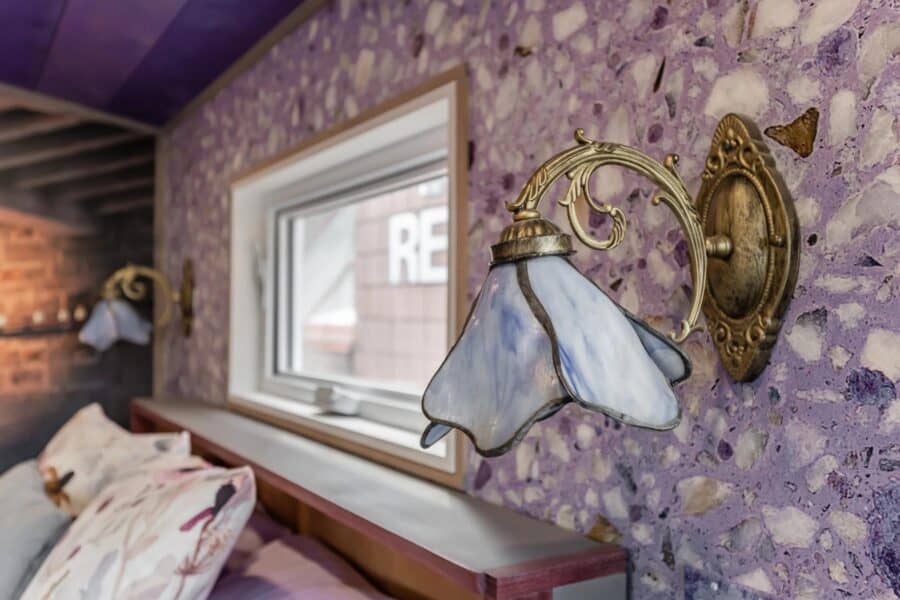Vintage wall-mounted lamp with purple floral shade in tiny house interior.